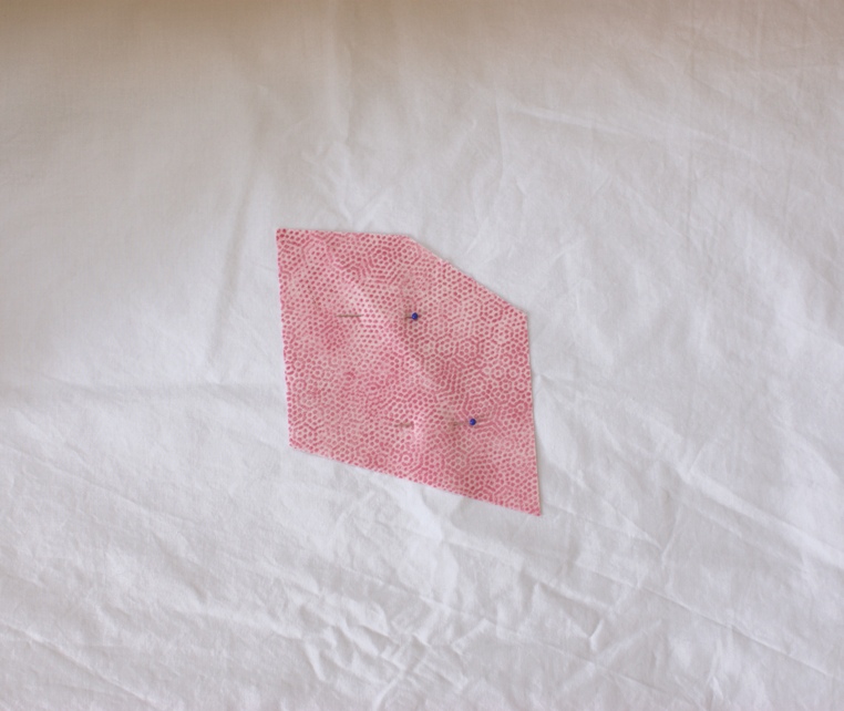 Start by pinning an irregular shaped fabric piece face up in the centre of the backing fabric.