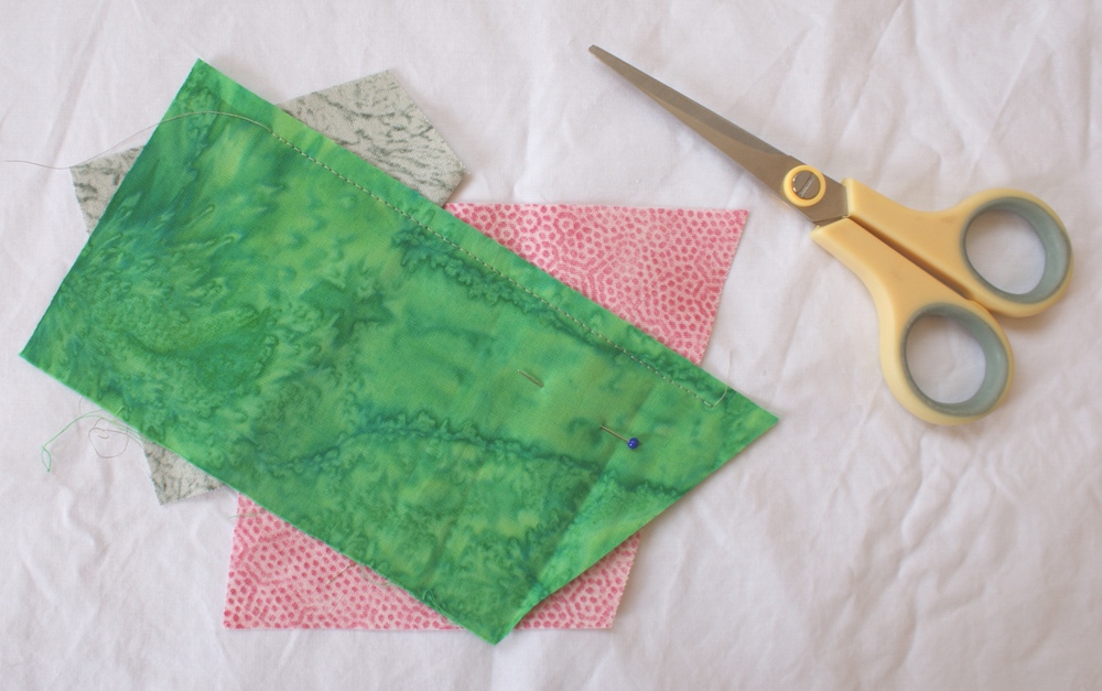 Add a third fabric piece long enough to cover the first two pieces. Position to ensure there is at least a quarter inch seam all along. After sewing the seam cut away excess fabrics poking beyond the allowance before flipping and pressing.
