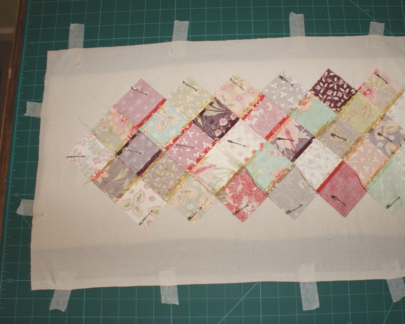 This method of creating a quilt sandwich invovled putting the wadding on the bottom, then the backing (right side up) and finally the patchwork, face down. I smoothed out the wadding then smoothed the backing over it, using masking tape to keep it taut without stretching it, then smoothed and pinned the top in place. Next step is to sew around the zig zag edge leaving a small gap to turn the runner inside out.